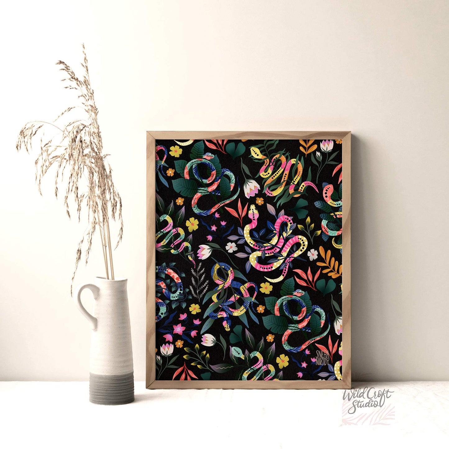 a vase with a plant in it next to a painting