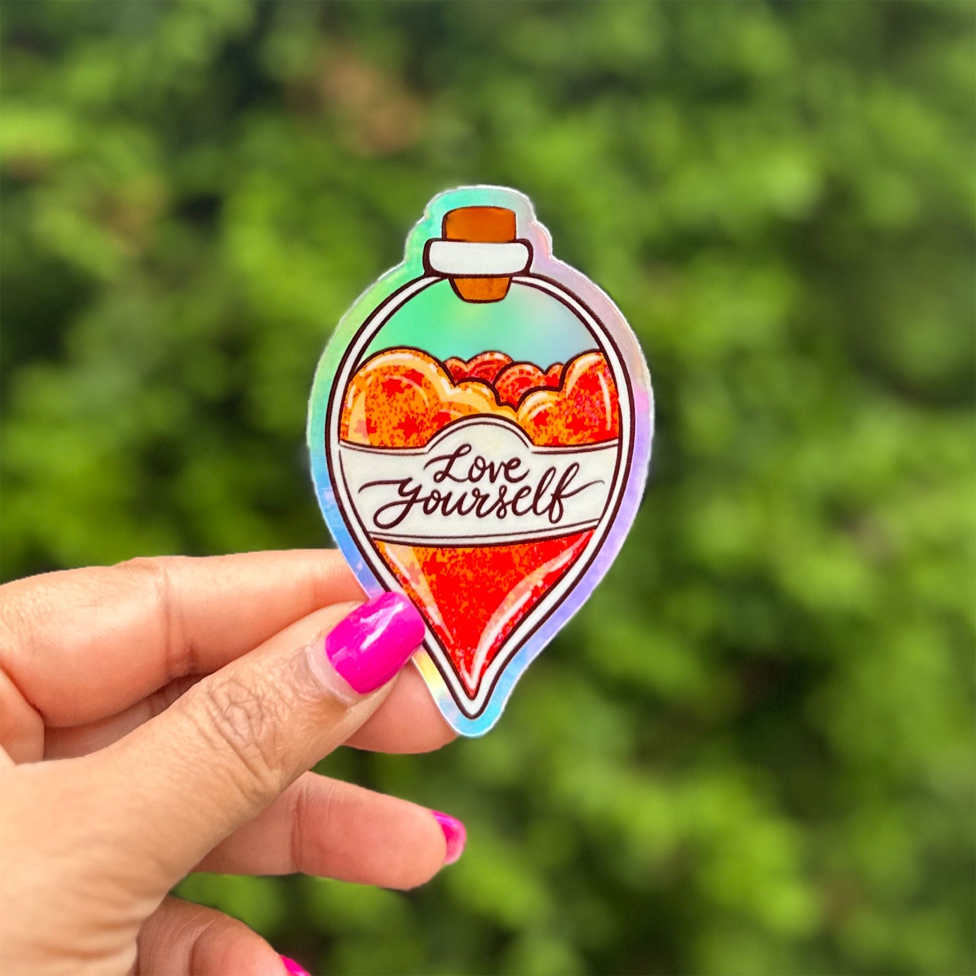 a hand holding a sticker that says love yourself