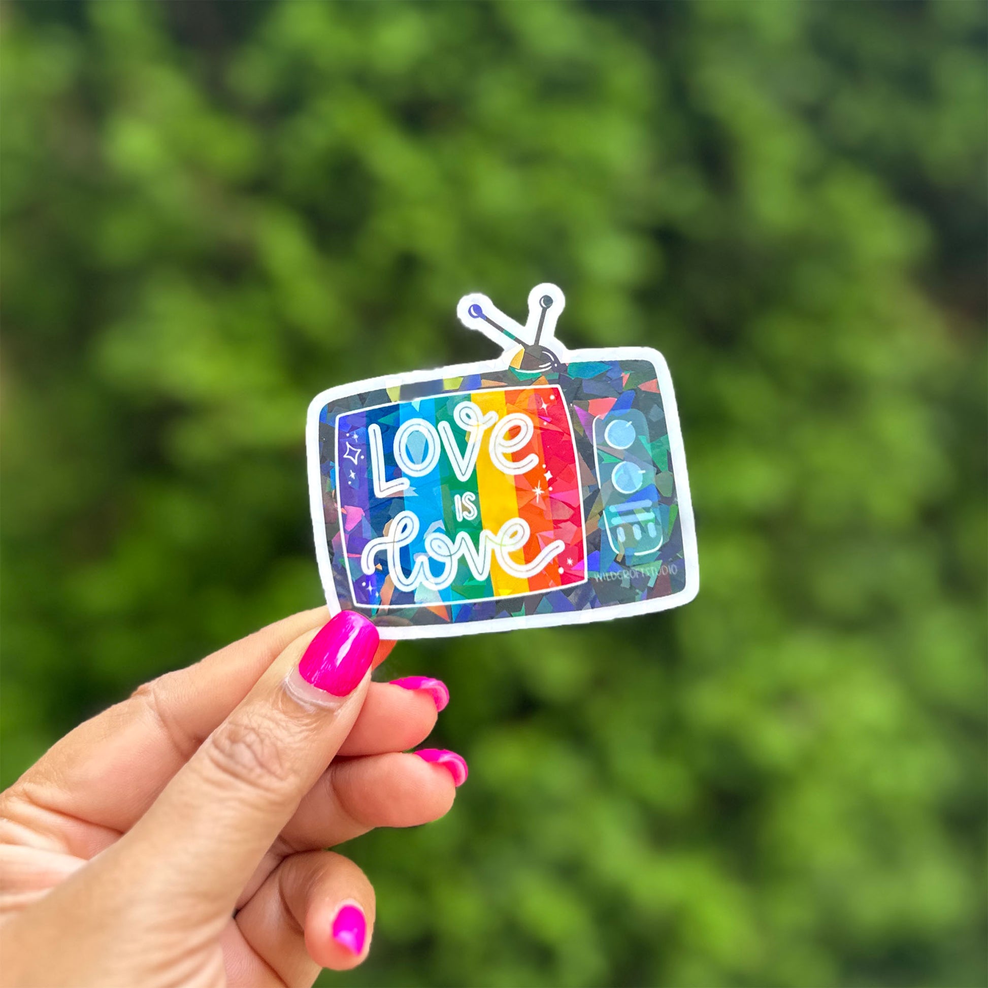 a hand holding a sticker with the words love is love on it