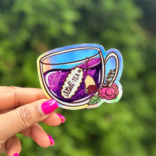 a hand holding a sticker of a cup of tea