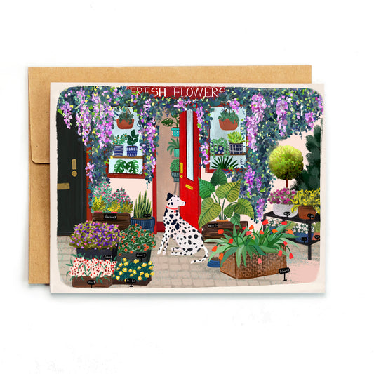a card with a dog sitting in front of a flower shop