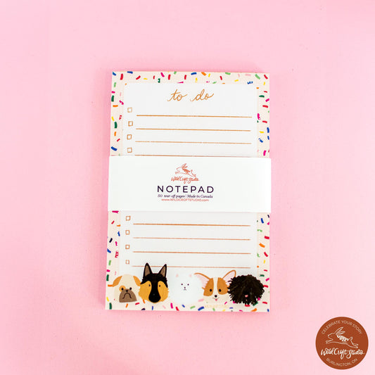 a notepad with dogs on it on a pink background