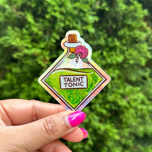 a hand holding a sticker of a bottle of talent tonic