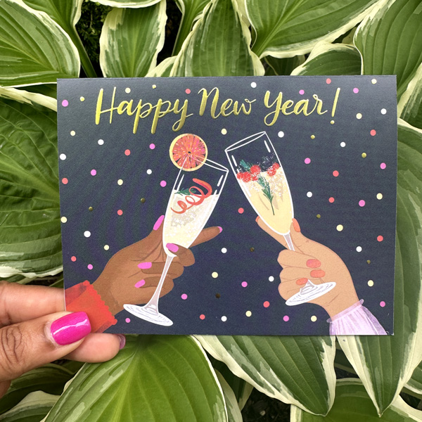 a hand holding a card with two glasses of champagne
