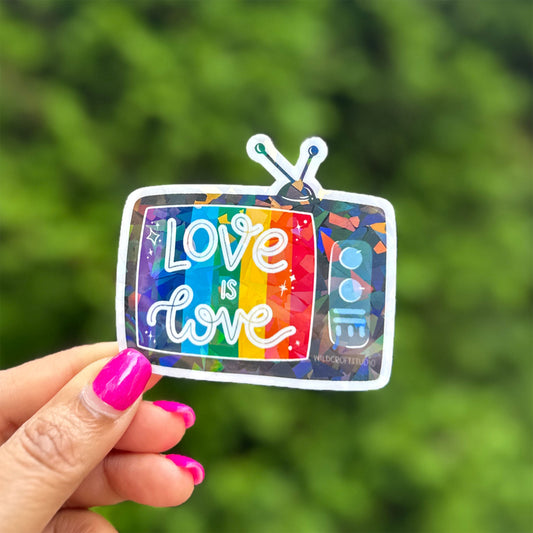 a hand holding a sticker with the words love is love on it