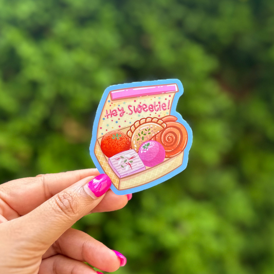 a hand holding a small sticker with a picture of a jar of candies