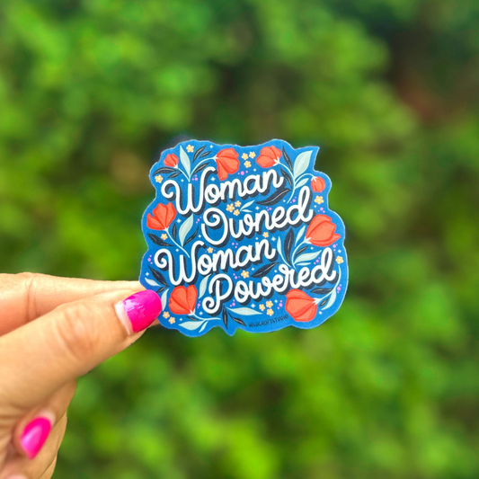 a woman is holding up a sticker that says woman owned woman powered