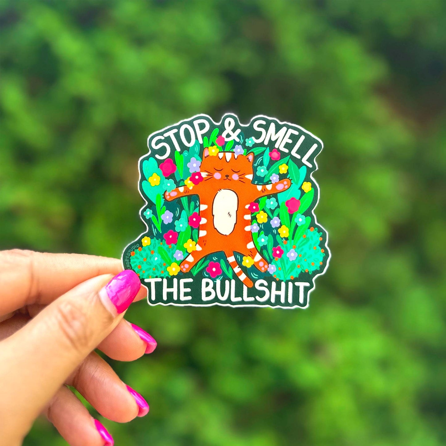 a hand holding a sticker that says stop and smell the bullshit